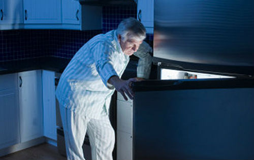 man looking in fridge with pajamas on