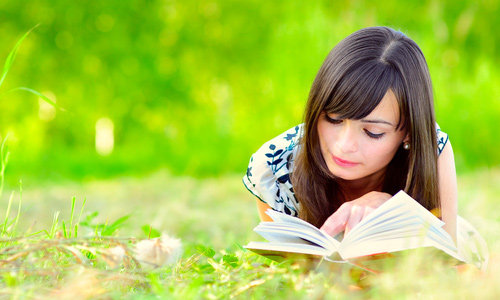 cute girl reading while laying on grass